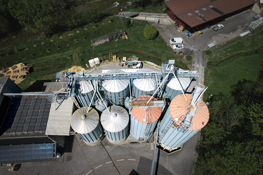 Aerial view of the Moulin de la Vaux industrial silos and solar panels surrounded by green fields and trees in Aubonne Vaud Switzerland. Aerial view of the Moulin de la Vaux industrial silos and solar panels surrounded by green fields and trees in Aubonne Vaud Switzerland.