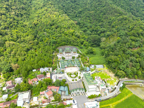 Aerial view of the Chung Tai Chan Monastery surrounded by lush green mountains terraced fields and small residential buildings in Puli Township Nantou County Taiwan. Aerial view of the Chung Tai Chan Monastery surrounded by lush green mountains terraced fields and small residential buildings in Puli Township Nantou County Taiwan.