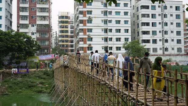 View of people crossing a bamboo bridge in Dhaka Bangladesh.