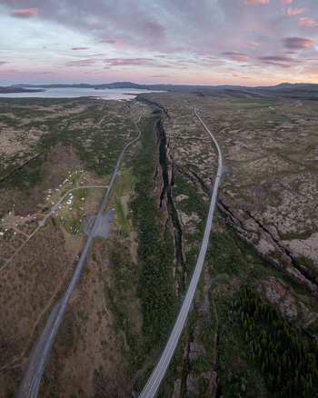 Aerial view of Thingvellir National Park featuring the Almannagja tectonic rift winding roads and mossy volcanic landscape under a soft sunset sky in Selfoss Blaskogabyggd Iceland. Aerial view of Thingvellir National Park featuring the Almannagja tectonic rift winding roads and mossy volcanic landscape under a soft sunset sky in Selfoss Blaskogabyggd Iceland.