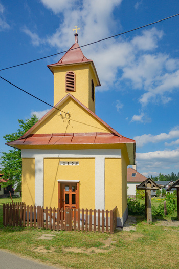 View of a small vibrant yellow chapel with a red roof stands proudly against a backdrop of a blue sky with fluffy clouds Donovaly Banskobystricky kraj Slovakia. View of a small vibrant yellow chapel with a red roof stands proudly against a backdrop of a blue sky with fluffy clouds Donovaly Banskobystricky kraj Slovakia.