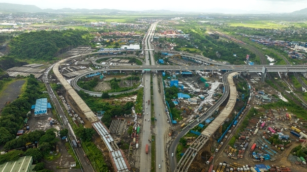 Aerial view of the JNPT Interchange featuring complex highway flyovers industrial infrastructure and surrounding greenery in Navi Mumbai Maharashtra India. Aerial view of the JNPT Interchange featuring complex highway flyovers industrial infrastructure and surrounding greenery in Navi Mumbai Maharashtra India.