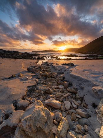 View of Blowholes Road at sunset with a rocky sandy beach dramatic clouds and ocean waves in Torndirrup Western Australia Australia. View of Blowholes Road at sunset with a rocky sandy beach dramatic clouds and ocean waves in Torndirrup Western Australia Australia.