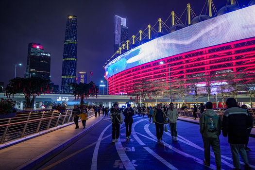 Guangzhou Guangdong Province China 24 February 2024 View of people walking on a pedestrian bridge at night with the illuminated Haixinsha Asian Games Park and skyscrapers. Guangzhou Guangdong Province China 24 February 2024 View of people walking on a pedestrian bridge at night with the illuminated Haixinsha Asian Games Park and skyscrapers.