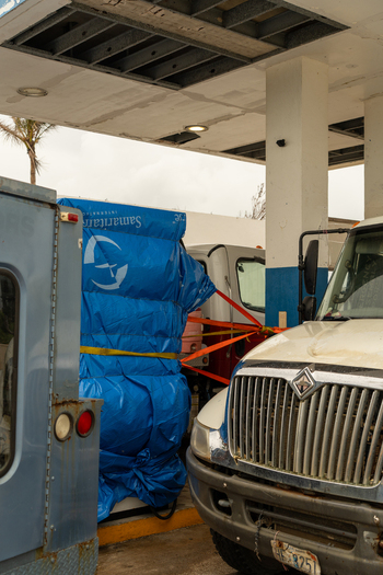 San Jose Tinian Northern Mariana Islands 05 July 2026 View of emergency relief supplies wrapped in blue tarps secured to a truck at a gas station. San Jose Tinian Northern Mariana Islands 05 July 2026 View of emergency relief supplies wrapped in blue tarps secured to a truck at a gas station.