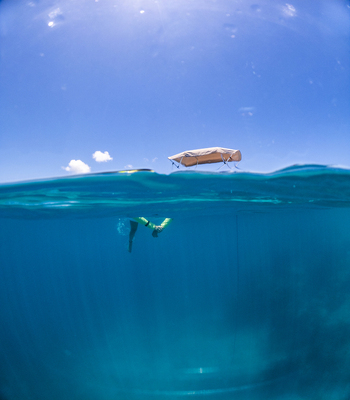 View of a person snorkeling in crystal clear blue water with a small boat floating on the surface Guanaja Bay Islands Department Honduras. View of a person snorkeling in crystal clear blue water with a small boat floating on the surface Guanaja Bay Islands Department Honduras.