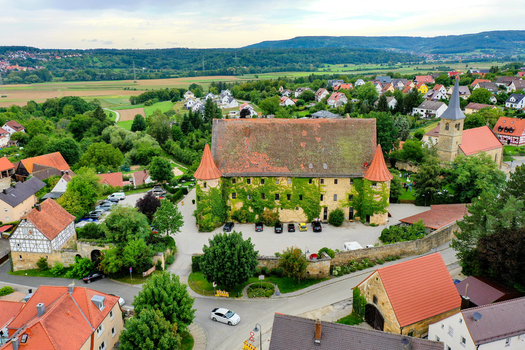 Wiesenthau Germany 09 May 2026 Aerial view of Schloss Wiesenthau with its ivy covered stone walls and red tiled roof surrounded by village houses and green hills. Wiesenthau Germany 09 May 2026 Aerial view of Schloss Wiesenthau with its ivy covered stone walls and red tiled roof surrounded by village houses and green hills.