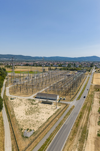 Aerial view of the Amprion Umspannwerk electrical substation with metal power structures and transformers surrounded by fields and a road in Pfungstadt Hessen Germany.