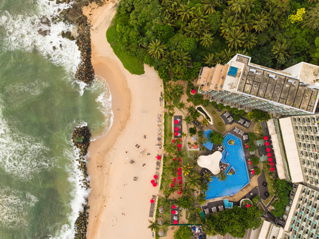 Aerial view of Dadalla beach featuring a modern resort with a swimming pool dense palm trees and ocean waves crashing against the shore in Galle Southern Province Sri Lanka. Aerial view of Dadalla beach featuring a modern resort with a swimming pool dense palm trees and ocean waves crashing against the shore in Galle Southern Province Sri Lanka.