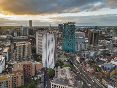 Aerial view of the Birmingham city skyline featuring the iconic green Rotunda building modern high rise architecture and urban roads under a sunset sky in Birmingham England United Kingdom.