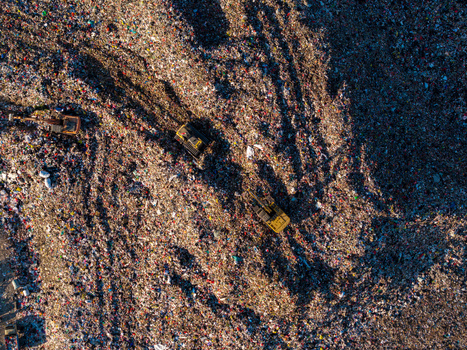 Aerial view of TPA Suwung landfill with heavy machinery excavators working on piles of waste in Kecamatan Denpasar Selatan Bali Indonesia.