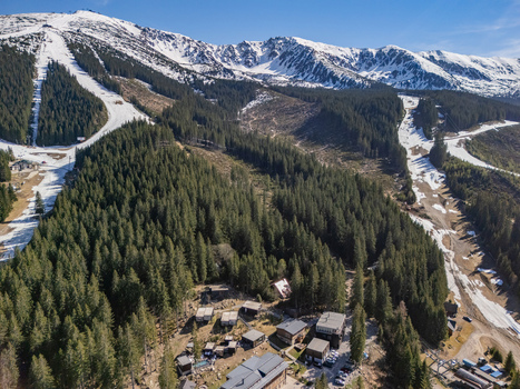 Aerial view of ski slopes dense pine forests and snow capped mountain peaks Demanovska Dolina Zilina Region Slovakia.