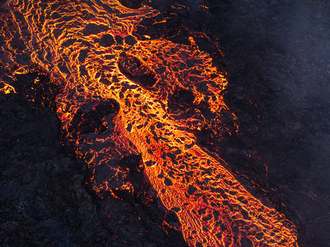 Aerial view of molten lava flowing through dark volcanic rock in Iceland. Aerial view of molten lava flowing through dark volcanic rock in Iceland.