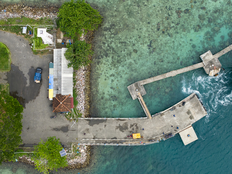 Aerial view of the concrete pier stretching into the turquoise sea where waves crash against the pilings near Karimunjawa ferry harbour Karimunjawa Jawa Tengah Indonesia. Aerial view of the concrete pier stretching into the turquoise sea where waves crash against the pilings near Karimunjawa ferry harbour Karimunjawa Jawa Tengah Indonesia.