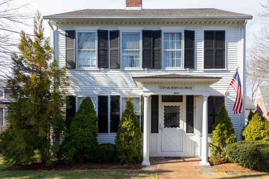 Edgartown United States 14 May 2026 View of the historic Captain Henry Colt House featuring white siding black shutters and an American flag under a clear sky.