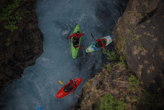 View of kayakers navigating the turquoise waters of Rio Manso between steep rocky canyon walls in San Carlos de Bariloche Rio Negro Argentina. View of kayakers navigating the turquoise waters of Rio Manso between steep rocky canyon walls in San Carlos de Bariloche Rio Negro Argentina.