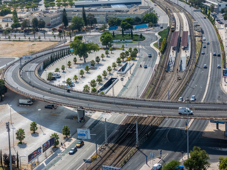 Aerial view of the Alges roundabout and railway station infrastructure surrounded by urban roads and palm trees in Alges Lisbon Portugal.