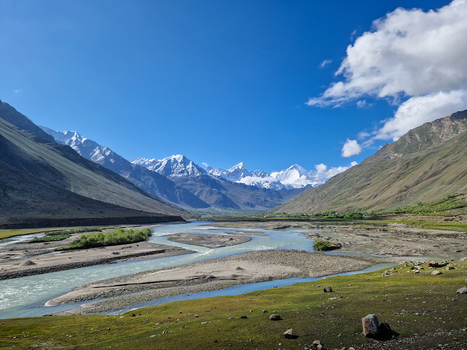 View of the winding river flowing through the Zanskar valley with snow capped Himalayan peaks in the background under a clear blue sky in Zanskar Ladakh India.