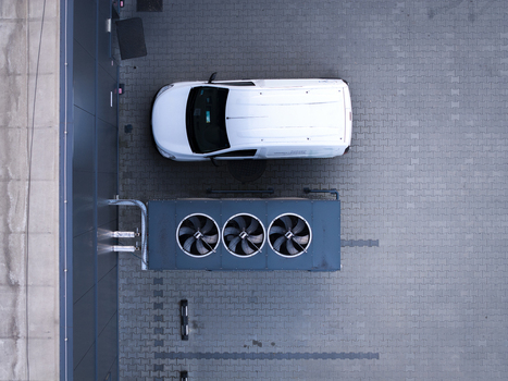 Aerial view of a white delivery van parked next to a large industrial air conditioning unit on a paved lot Poland. Aerial view of a white delivery van parked next to a large industrial air conditioning unit on a paved lot Poland.