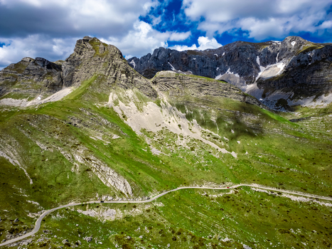 Aerial view of Bobotov Kuk winding mountain road rocky peaks green slopes and blue sky in Zabljak Municipality Montenegro. Aerial view of Bobotov Kuk winding mountain road rocky peaks green slopes and blue sky in Zabljak Municipality Montenegro.