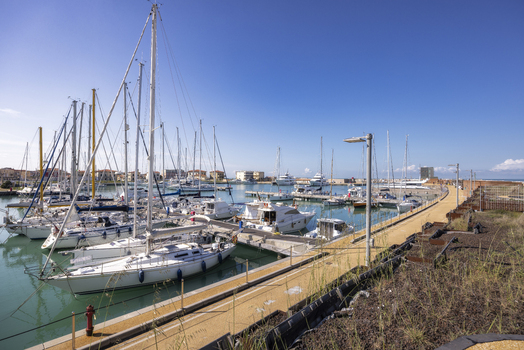 View of numerous sailboats and motorboats moored in the harbor under a clear blue sky at Marina di Pisa Tuscany Italy.