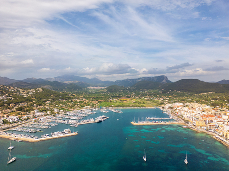 Aerial view of Port d Andratx harbor with numerous yachts moored in the marina coastal buildings and rugged green mountains under a bright sky Port d Andratx Balearic Islands Spain. Aerial view of Port d Andratx harbor with numerous yachts moored in the marina coastal buildings and rugged green mountains under a bright sky Port d Andratx Balearic Islands Spain.