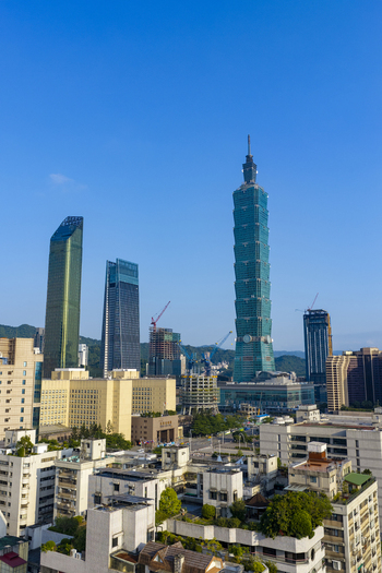 Aerial view of Taipei 101 skyscraper rising above the modern urban skyline with glass towers construction cranes and dense residential rooftops under a clear blue sky in Taipei Taiwan. Aerial view of Taipei 101 skyscraper rising above the modern urban skyline with glass towers construction cranes and dense residential rooftops under a clear blue sky in Taipei Taiwan.