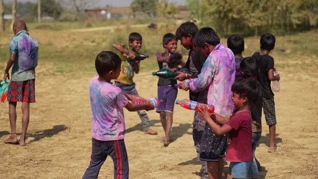 View of children playing with colored water in a dusty field Nepal.