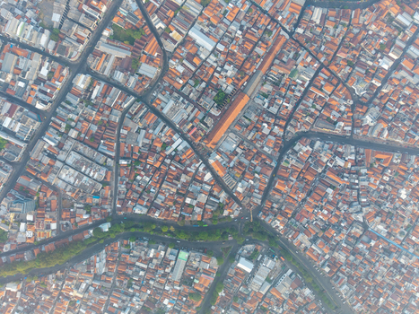 Aerial view of the historic Surabaya old town with dense terracotta tiled rooftops narrow streets and a winding river in Surabaya East Java Indonesia.