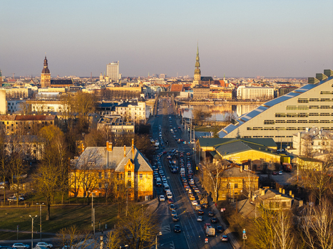 Aerial view of the historic skyline of Riga featuring the National Library of Latvia the Stone Bridge crossing the Daugava river and church spires bathed in warm sunset light. Riga Latvia.