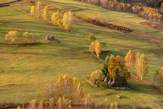 View of a rural landscape with traditional haystacks and autumn trees in the rolling hills of Alba Iulia Alba County Romania. View of a rural landscape with traditional haystacks and autumn trees in the rolling hills of Alba Iulia Alba County Romania.