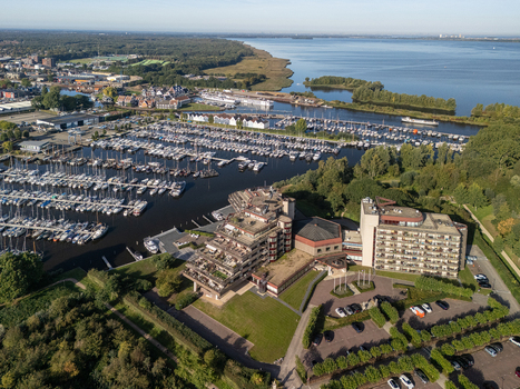 Aerial view of the marina with numerous sailboats and motorboats docked modern apartment buildings and lush green surroundings in Huizen North Holland Netherlands.
