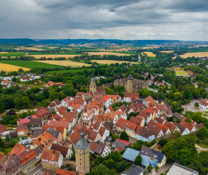 Aerial view of Schloss Neuenstein and the historic town center with red tiled rooftops church towers and surrounding green fields in Neuenstein Baden Wurttemberg Germany. Aerial view of Schloss Neuenstein and the historic town center with red tiled rooftops church towers and surrounding green fields in Neuenstein Baden Wurttemberg Germany.