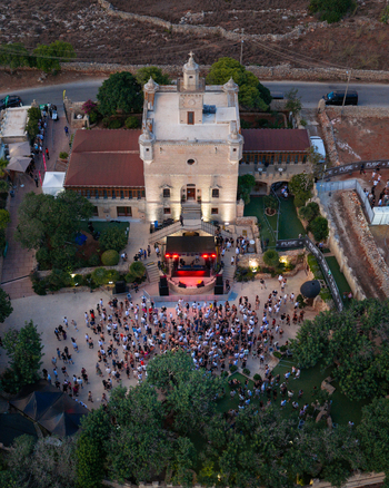 Mgarr Northern Region Malta 17 September 2026 Aerial view of Castello Zamittello hosting an outdoor event with a crowd of people gathered in the courtyard near a stage with red lighting. Mgarr Northern Region Malta 17 September 2026 Aerial view of Castello Zamittello hosting an outdoor event with a crowd of people gathered in the courtyard near a stage with red lighting.