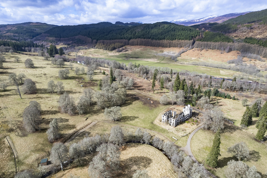 Aerial view of the historic Guisachan House ruins in the landscape of Glen Affric surrounded by meadows trees and rolling hills in Beauly Glen Affric Scotland United Kingdom. Aerial view of the historic Guisachan House ruins in the landscape of Glen Affric surrounded by meadows trees and rolling hills in Beauly Glen Affric Scotland United Kingdom.