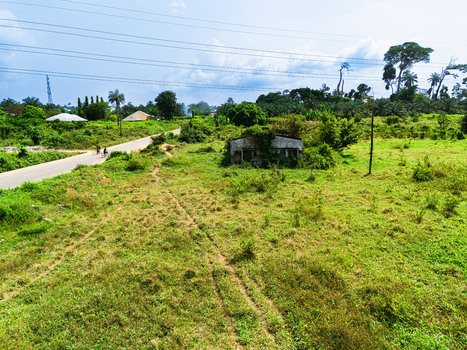 Aerial view of a rural landscape featuring an overgrown building a paved road and lush green vegetation in Ahoada I Rivers Nigeria. Aerial view of a rural landscape featuring an overgrown building a paved road and lush green vegetation in Ahoada I Rivers Nigeria.