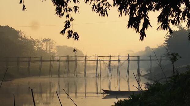 View of a bamboo bridge over a river at sunrise Bangladesh.