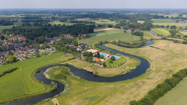 Aerial view of the Berkel river winding through the green landscape with a swimming pool complex and the village of Almen in the background Almen Gelderland Netherlands. Aerial view of the Berkel river winding through the green landscape with a swimming pool complex and the village of Almen in the background Almen Gelderland Netherlands.