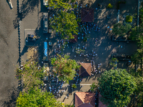 Aerial view of Ngelarung Sea Offering Ceremony at Pura Segara Goa Lawah with people in traditional Balinese attire gathered in the temple courtyard in Dawan Bali Indonesia.