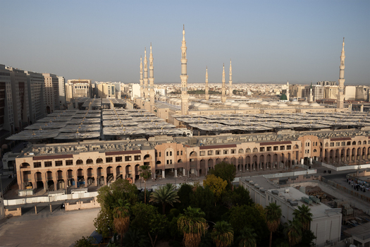 View of the Al Masjid e Nabawi with its iconic minarets and expansive courtyard covered by large white umbrellas in Madinah Al Madinah Province Saudi Arabia.
