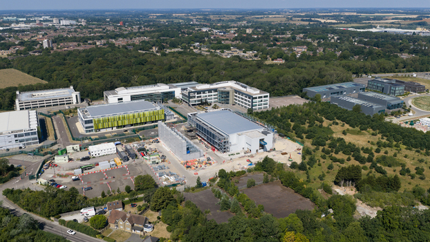 Aerial view of the Kao Data campus featuring modern office buildings and a construction site surrounded by lush greenery in Harlow England United Kingdom. Aerial view of the Kao Data campus featuring modern office buildings and a construction site surrounded by lush greenery in Harlow England United Kingdom.