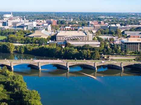Aerial view of the historic Washington Street Bridge spanning the White River with lush trees and the urban skyline in the background in Indianapolis Indiana United States. Aerial view of the historic Washington Street Bridge spanning the White River with lush trees and the urban skyline in the background in Indianapolis Indiana United States.