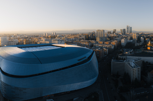 Aerial view of the Santiago Bernabeu stadium featuring its modern metallic facade and surrounding urban skyline during golden hour in Madrid Community of Madrid Spain. Aerial view of the Santiago Bernabeu stadium featuring its modern metallic facade and surrounding urban skyline during golden hour in Madrid Community of Madrid Spain.