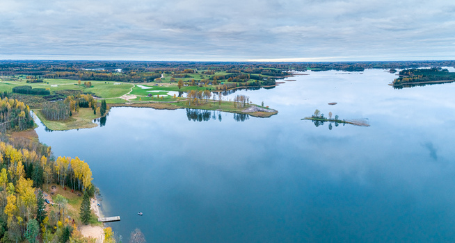 Aerial view of the serene lake in Cesis surrounded by autumn forests green meadows and calm waters under a cloudy sky in Cesis Cesis Municipality Latvia. Aerial view of the serene lake in Cesis surrounded by autumn forests green meadows and calm waters under a cloudy sky in Cesis Cesis Municipality Latvia.