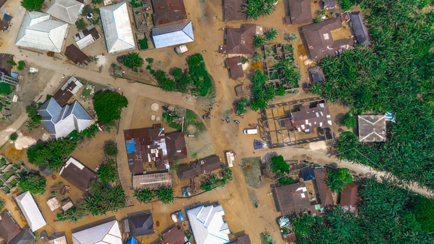 Aerial view of a rural settlement with scattered houses metal roofs and dirt paths surrounded by lush vegetation in Abua Rivers Nigeria. Aerial view of a rural settlement with scattered houses metal roofs and dirt paths surrounded by lush vegetation in Abua Rivers Nigeria.