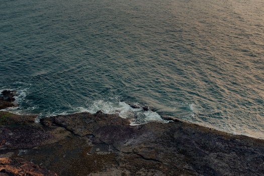View of the waves crashing against the rugged rocky shore where the deep blue sea meets the textured earth creating a striking contrast Chiplun Maharashtra India. View of the waves crashing against the rugged rocky shore where the deep blue sea meets the textured earth creating a striking contrast Chiplun Maharashtra India.
