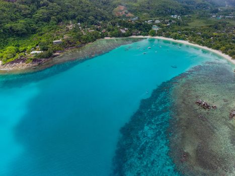 Aerial view of turquoise waters meet the sandy shore fringed by verdant hills and scattered buildings creating a vibrant contrast of colors and textures Victoria Mahe Island Seychelles. Aerial view of turquoise waters meet the sandy shore fringed by verdant hills and scattered buildings creating a vibrant contrast of colors and textures Victoria Mahe Island Seychelles.