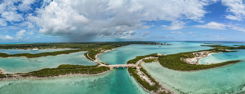 Aerial view of the stone bridge at Crab Cay connecting tropical islands surrounded by turquoise waters and lush greenery under a dramatic cloudy sky in Exuma Exuma The Bahamas. Aerial view of the stone bridge at Crab Cay connecting tropical islands surrounded by turquoise waters and lush greenery under a dramatic cloudy sky in Exuma Exuma The Bahamas.