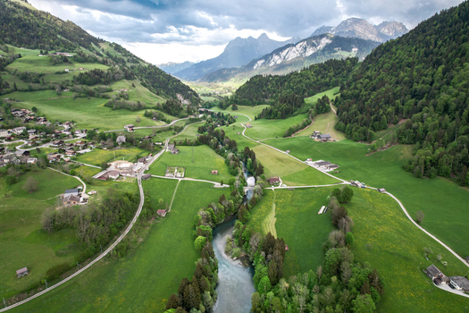 Aerial view of Lac du Vernex and the Sarine river winding through lush green meadows and the alpine village of Rossiniere Vaud Switzerland.