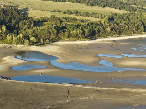 Aerial view of shallow water pools in a sandy riverbed surrounded by lush green trees and rolling hills in Poland. Aerial view of shallow water pools in a sandy riverbed surrounded by lush green trees and rolling hills in Poland.